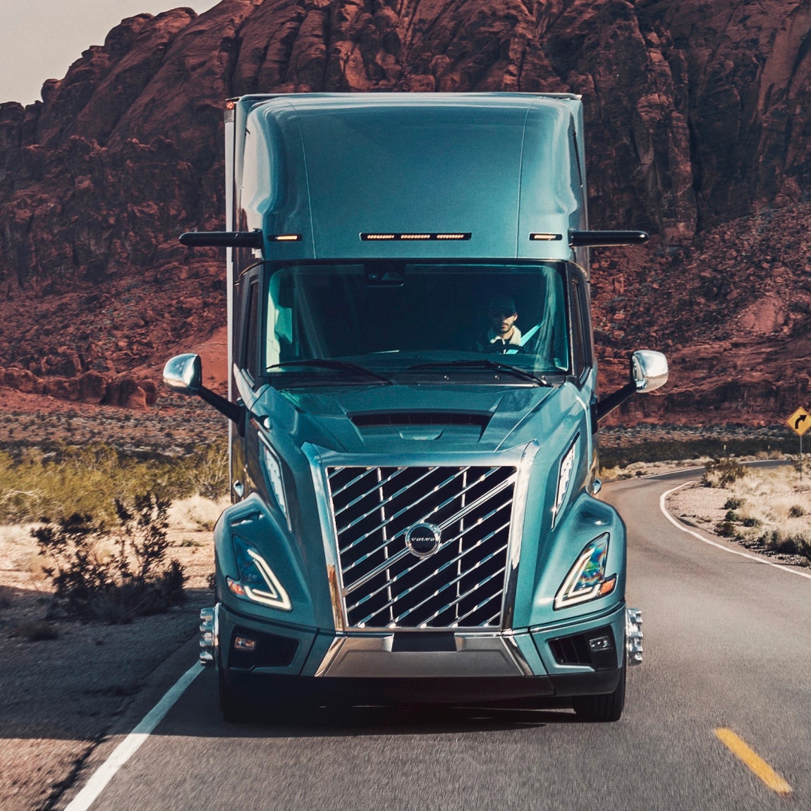 Front view of a heavy truck traveling through a scenic landscape, with bold grille and headlights
